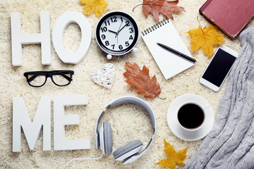 Fototapeta na wymiar Cup of coffee with smartphone, headphones, glasses, sweater and dried leafs