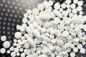White medicine pills on metal background