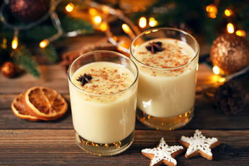 Eggnog in glasses with star anise and cookies on wooden table