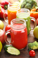 Vegetables smoothie in jars on wooden table