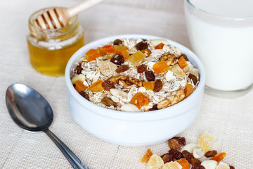 Healthy eating. On the wooden board are muesli, a spoon, a glass of milk, a jar of honey.