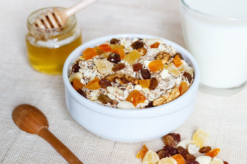 Healthy eating. On the wooden board are muesli, a spoon, a glass of milk, a jar of honey.