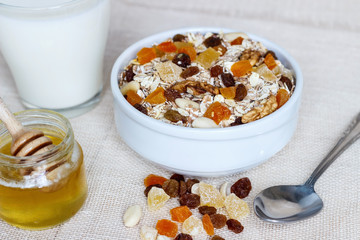Healthy eating. On the wooden board are muesli, a spoon, a glass of milk, a jar of honey.