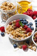 muesli with yogurt and berries for breakfast on white background, vertical
