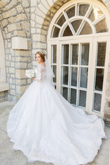 Fototapeta premium Portrait of a beautiful bride in a white dress and a bouquet of flowers in her hands
