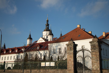 Fototapeta premium a white monastery with towering willows and a wrought-iron gate on a sunny day