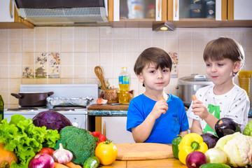 Healthy eating. Happy children prepares and eats vegetable salad in kitchen