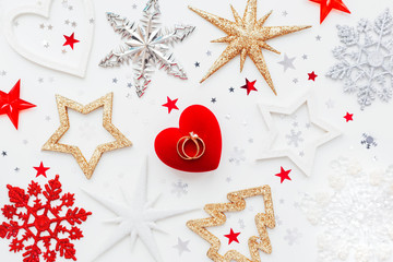 Christmas and New Year holiday background with decorations and wedding rings on gift heart box. Top view, flat lay.