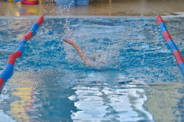 Freestyle swimming kids racing in turquoise clear indoor pool