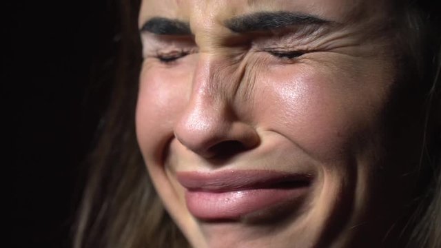Face of a beautiful brunette woman that shows disgust, abomination on a black background