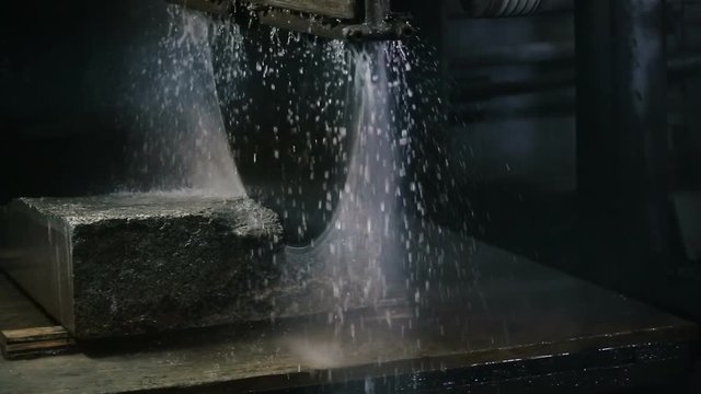 Circular saw cutting of Huge stone block of limestone. Granite processing in manufacturing. Cutting granite slab by a circular saw. Use of water for cooling