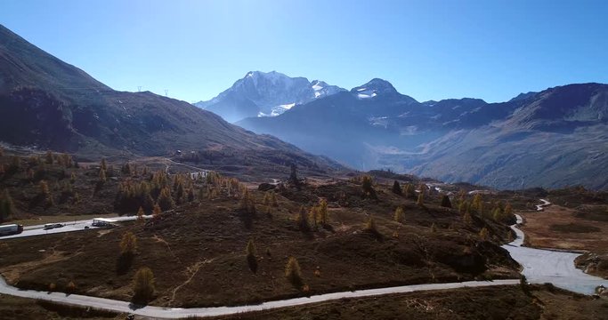 Alpine landscape, Cinema 4k aerial rising view over the top of simplon pass and away the eagle statue and snowy mountains, on a sunny autumn day, in Valais, alps of Switzerland