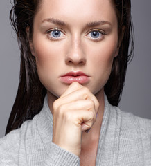 Naklejka premium Beauty portrait of young woman in gray dress. Brunette girl with bright blue eyes and day female makeup