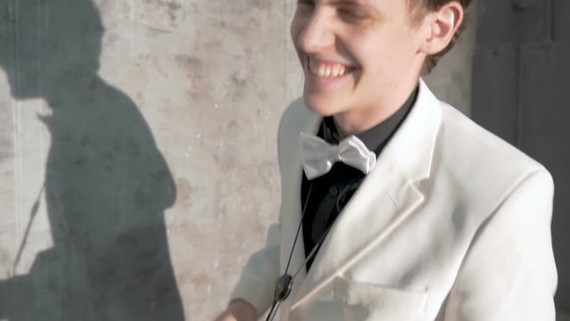 A musician in a white suit plays the saxophone. He performs in a nightclub, against a gray background. close-up