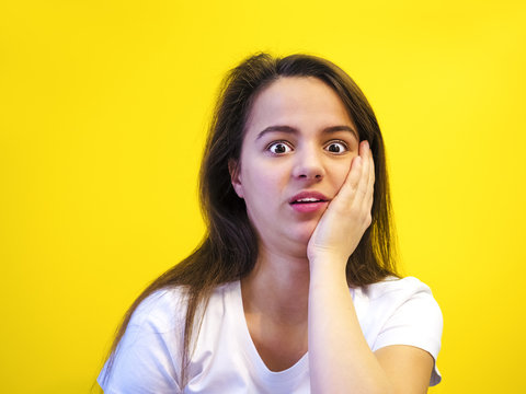 Negative facial expressions. young girl squeamish, close-up, isolated on yellow background