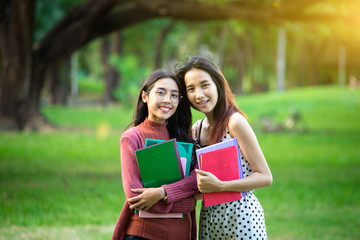 Fototapeta premium Portrait of high school girl with books in park, education concept