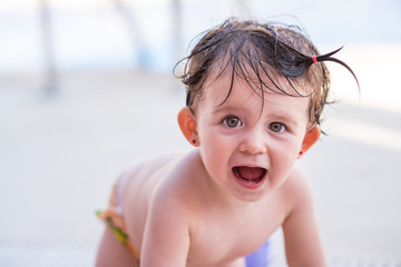 Retrato de una bebé feliz que acaba de salir de darse un baño en la piscina durante el verano,...