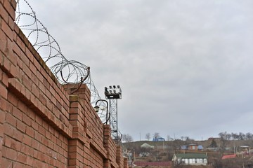 Old destroyed brick fence with barbed wire on field. Part of brick wall in ruins