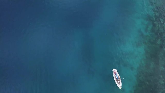 Sailing boat from above in blue waters - screw driver shot from drone
