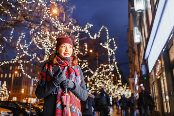 Obraz na płótnie Canvas Young woman tourist standing at illuminated alley christmas decoration