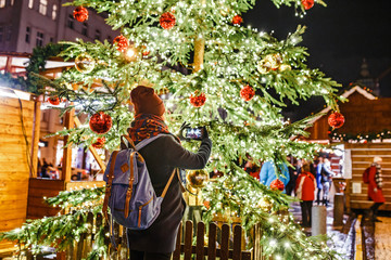 Woman tourist at night admiring the Christmas tree with lights in the main square of the European...