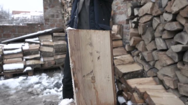 man splitting frozen wood with axe. wide shot slow motion