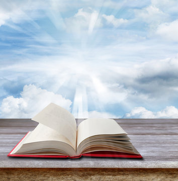 Open book on table in front of heavenly sunny sky