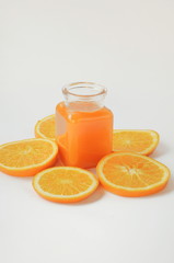 A glass bottle of orange juice with orange slices on white background. Vitamins on top view