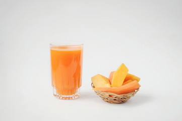 A glass of pumpkin and carrot juice with vegetables on white background. Pieces of pumpkin and carrot on straw plate. Vitamins