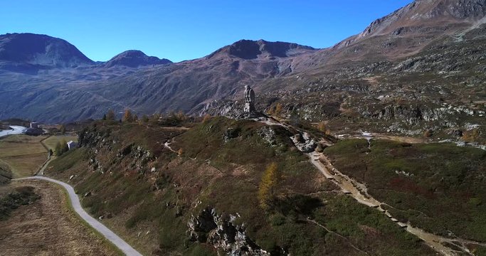 Stone statue, Cinema 4k aerial rising view of the bird statue monument, on the top of simplon pass, on a sunny autumn day, in Valais, Switzerland