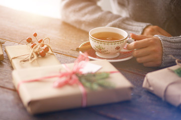Woman sitting on the desk with christmas gift box. Hands of woman