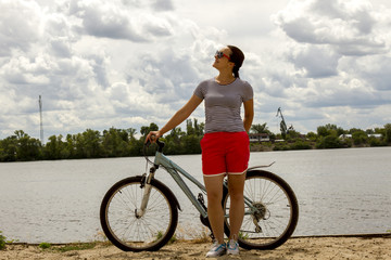 Fototapeta premium Image of a beautiful girl on the bike near river bank