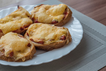 close-up of baked hot sandwiches with cheese and sausage on white plate