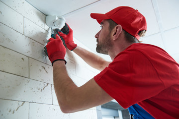 worker installing or adjusting motion sensor detector on the ceiling