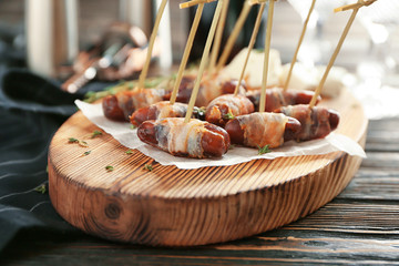 Wooden board with bacon wrapped dates on table