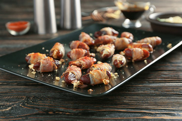 Plate with bacon wrapped dates on table