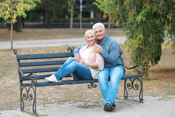 Mature couple sitting on bench outdoors