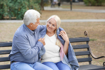 Mature couple sitting on bench outdoors