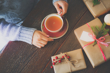 Woman sitting on the desk with christmas gift box. Hands of woman