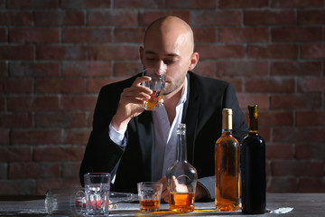 Man drinking whiskey at table. Alcoholism concept