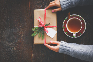 Woman sitting on the desk with christmas gift box. Hands of woman
