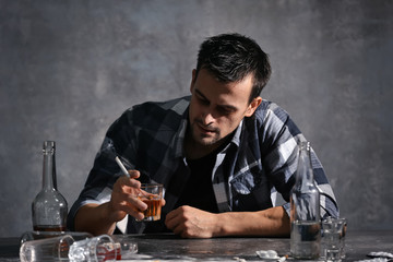 Man drinking alcohol and smoking cigarette while sitting at table