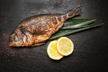 Tasty grilled fish on dark background