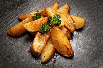 Pieces of tasty fried potato on dark background