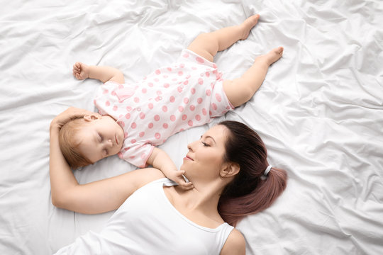 Young mother and cute sleeping baby on bed
