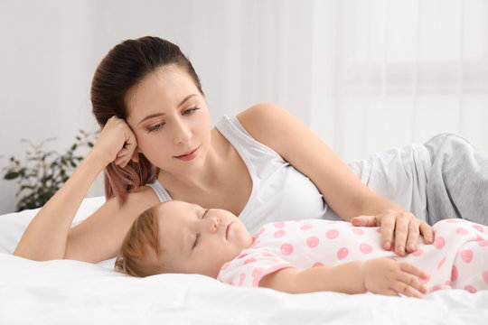 Young mother and cute sleeping baby on bed at home