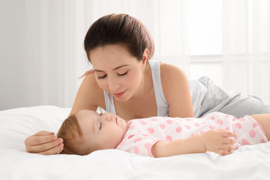 Young mother and cute sleeping baby on bed at home