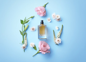 Bottle of perfume with flowers on color background
