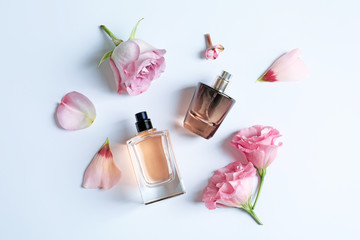Bottles of perfume with flowers on light background - obrazy, fototapety, plakaty