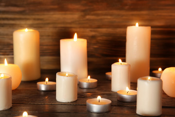 Fototapeta na wymiar Many burning candles on wooden background